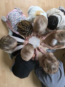 kinder im kreis beobachten den reis auf einer trommel