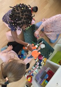 drei kinder spielen mit gehäkelten zwergen